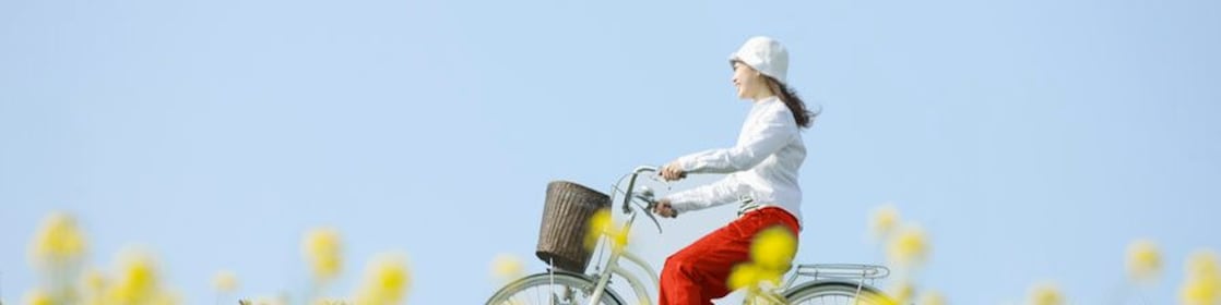 A young woman rides a bicycle through a summer field